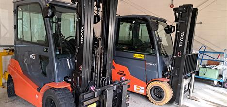 A pair of black and orange forklifts in a garage