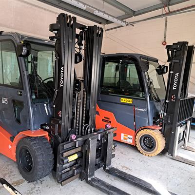 A pair of black and orange forklifts in a garage