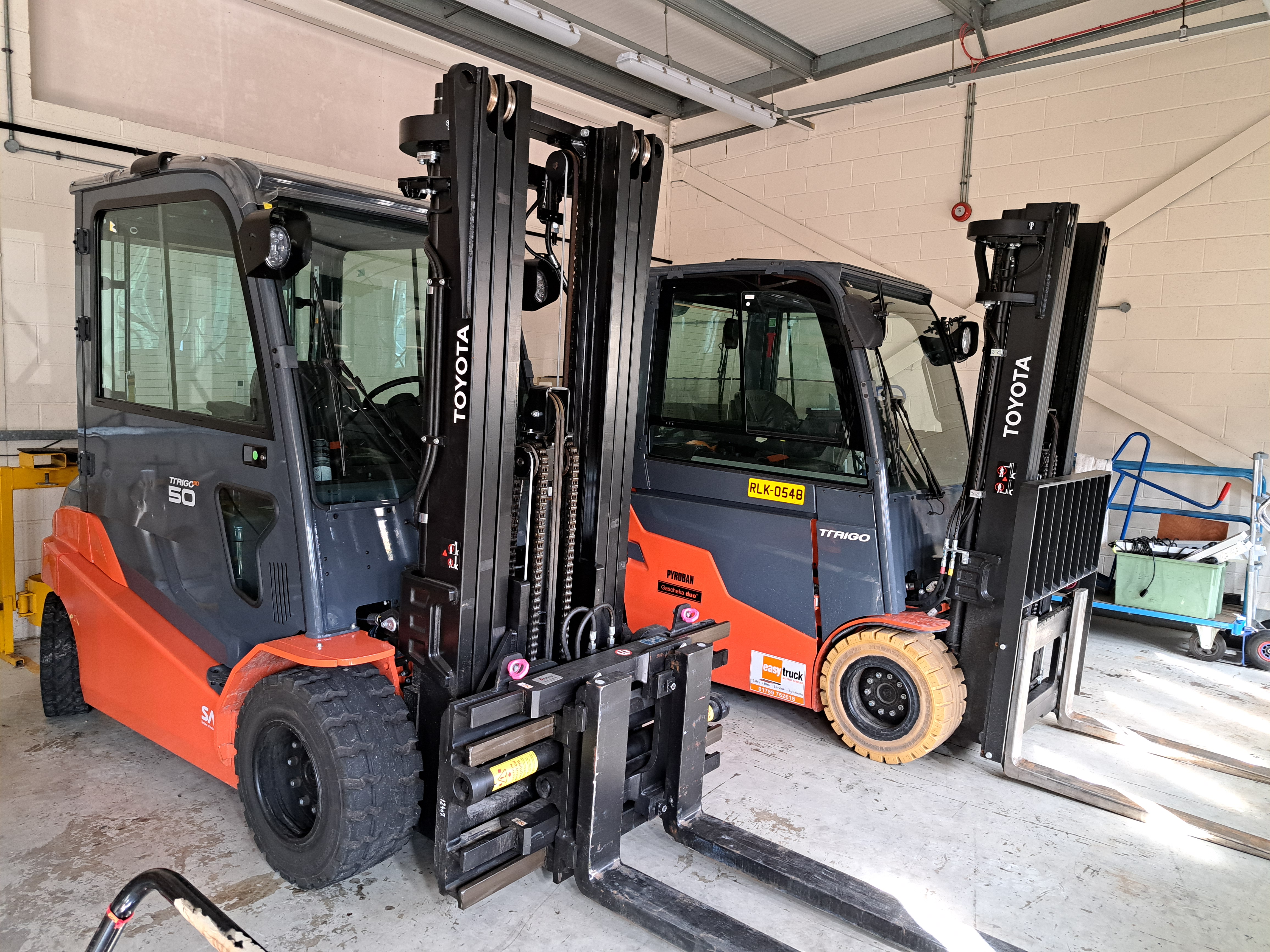 A pair of black and orange forklifts in a garage