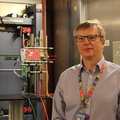 Chris Frost standing in the ChipIr blockhouse next to some sample electronic chips.