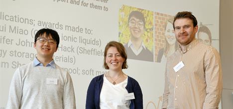 Three researchers standing in front of a projected image, facing towards the camera
