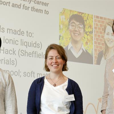 Three researchers standing in front of a projected image, facing towards the camera