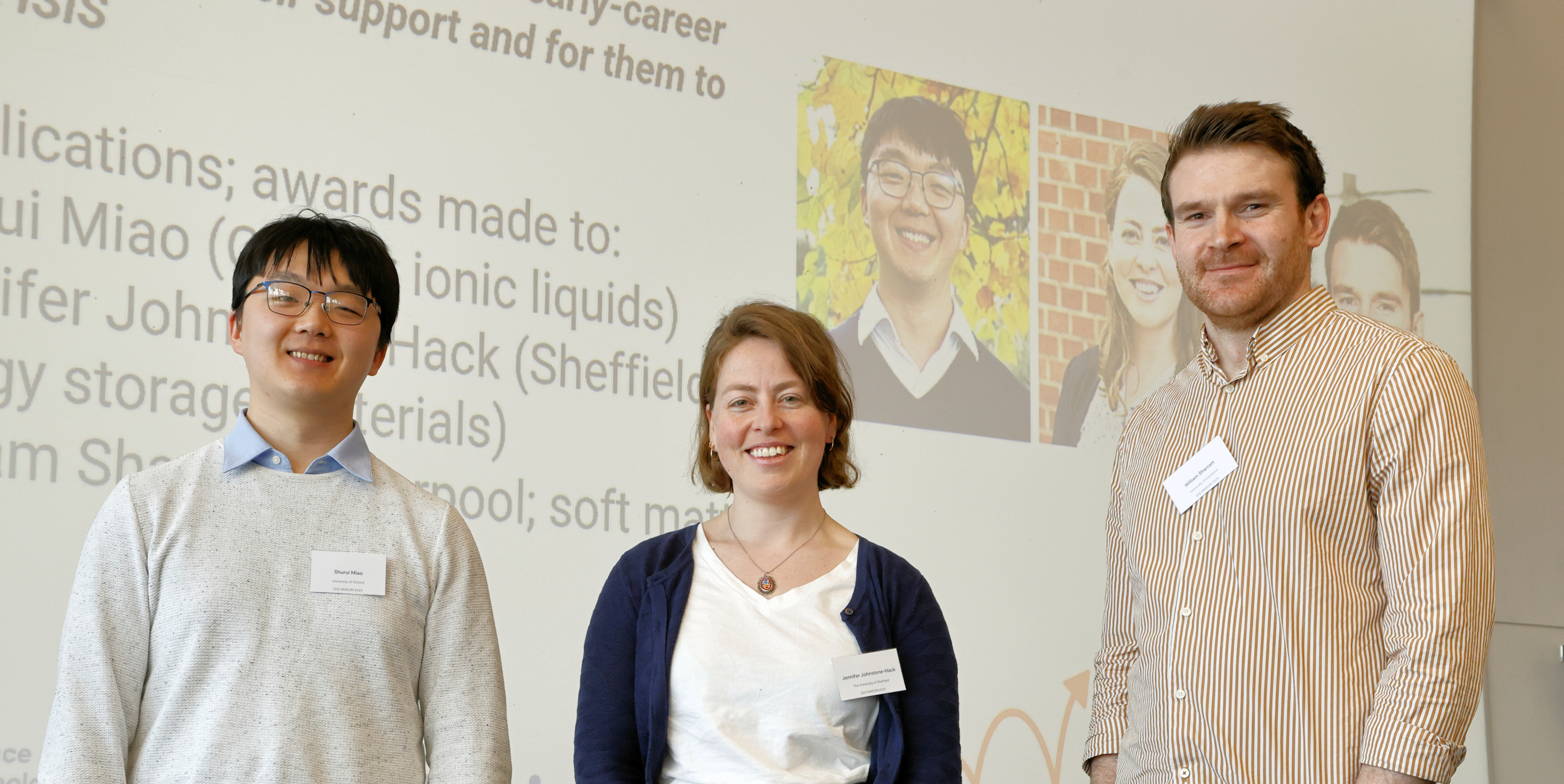Three researchers standing in front of a projected image, facing towards the camera