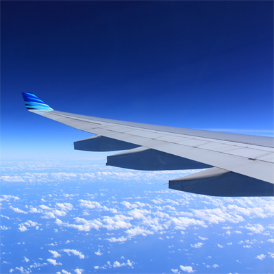 Cropped image showing a plane wing over a blue sky