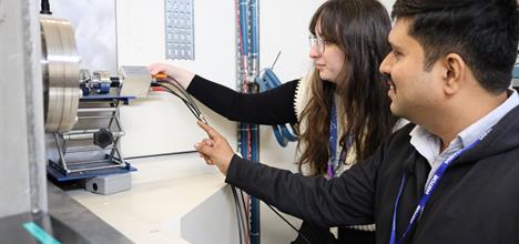 A man and a woman plugging in wires into a silver box
