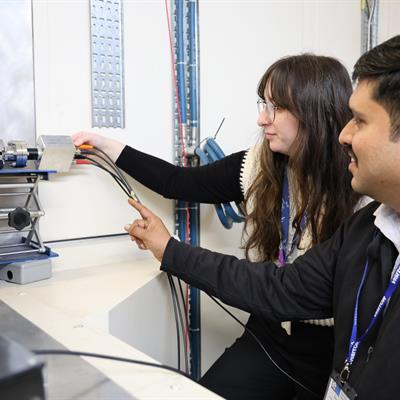 A man and a woman plugging in wires into a silver box