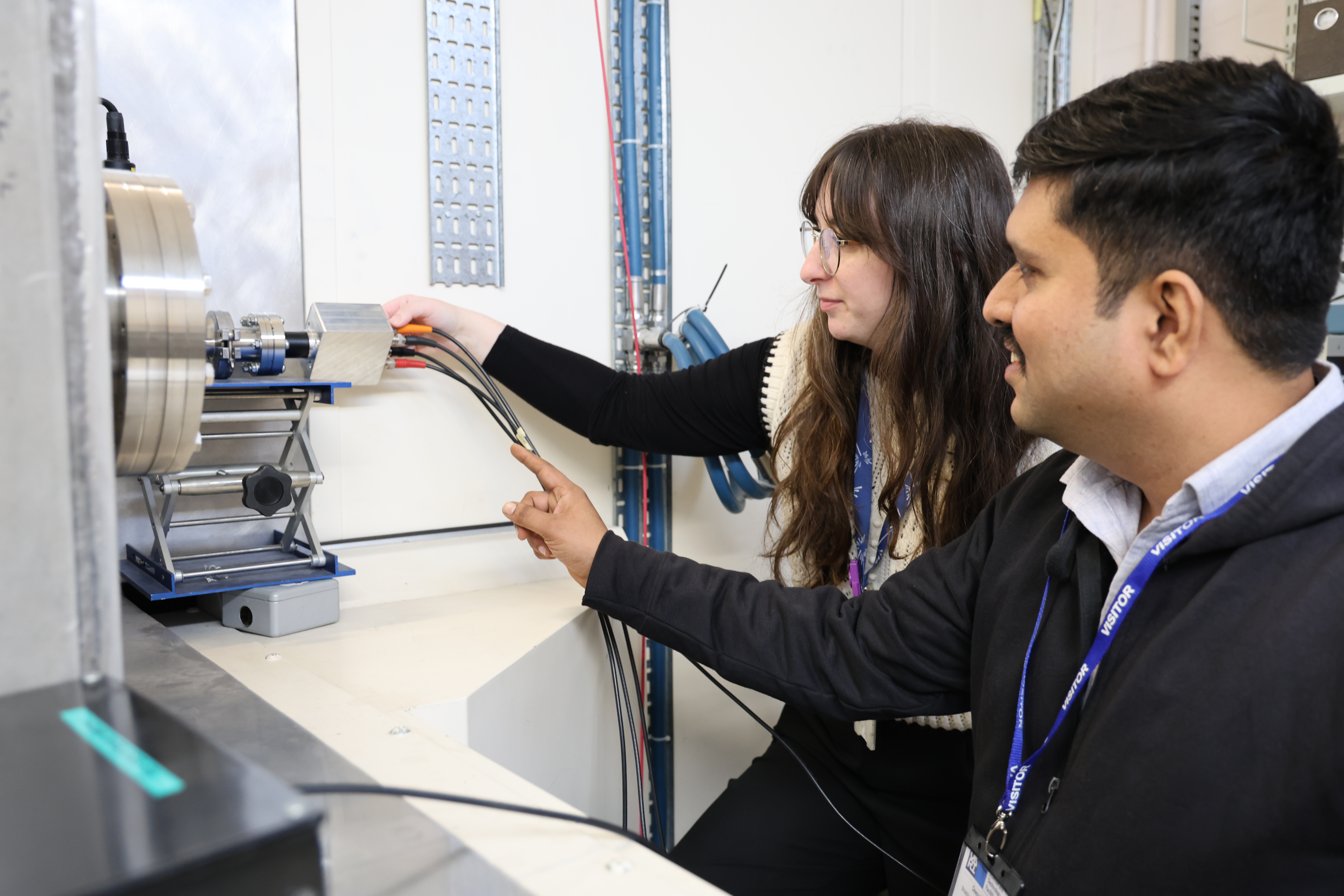 A man and a woman plugging in wires into a silver box