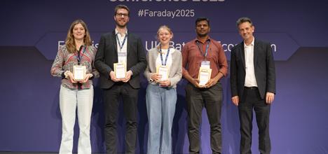 Four students holding prizes, all smiling on a stage
