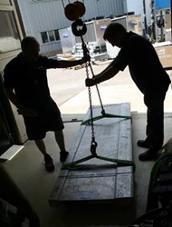 Two people using a crane to lift a large sample