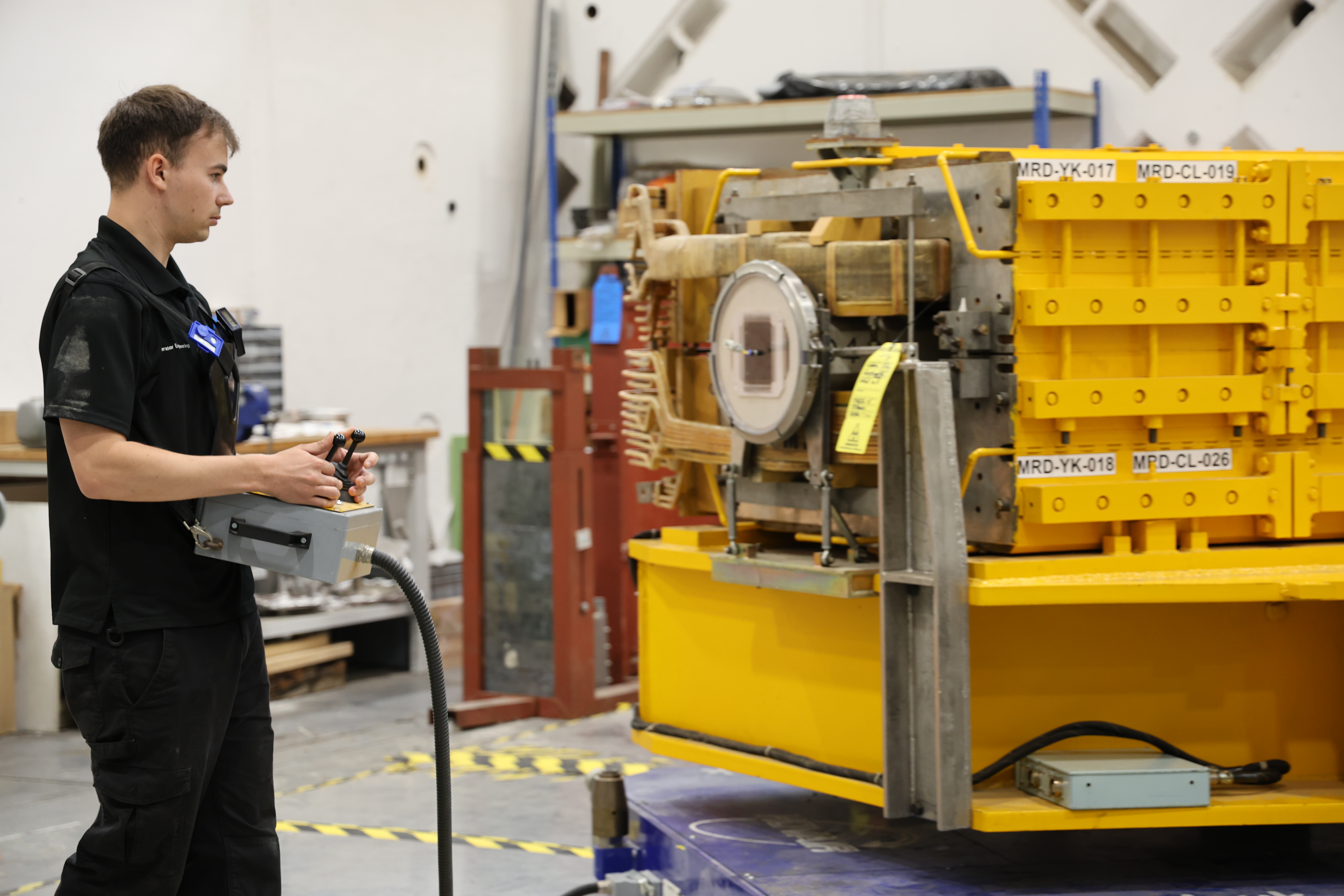 A man holding a controller next to a large magnet