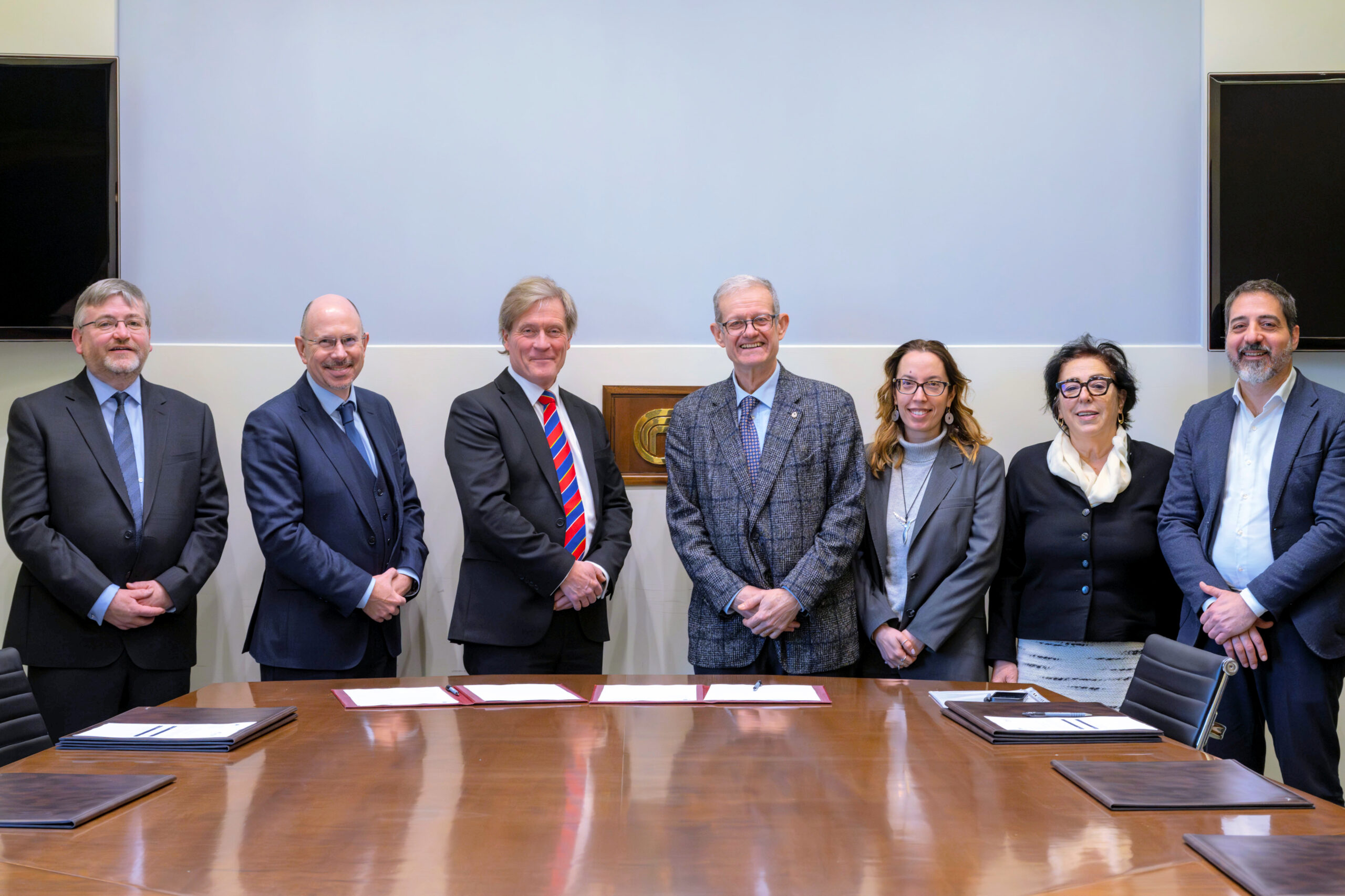 A group of people in suits standing behind a desk