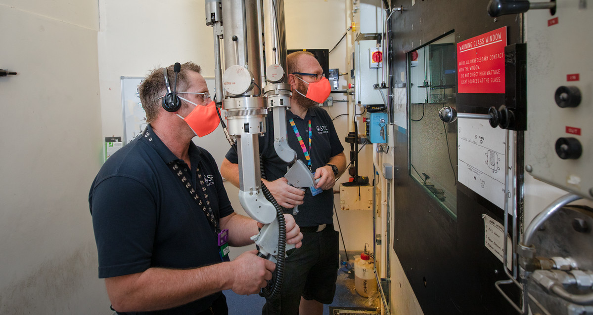 Two engineers using the remote handling arm