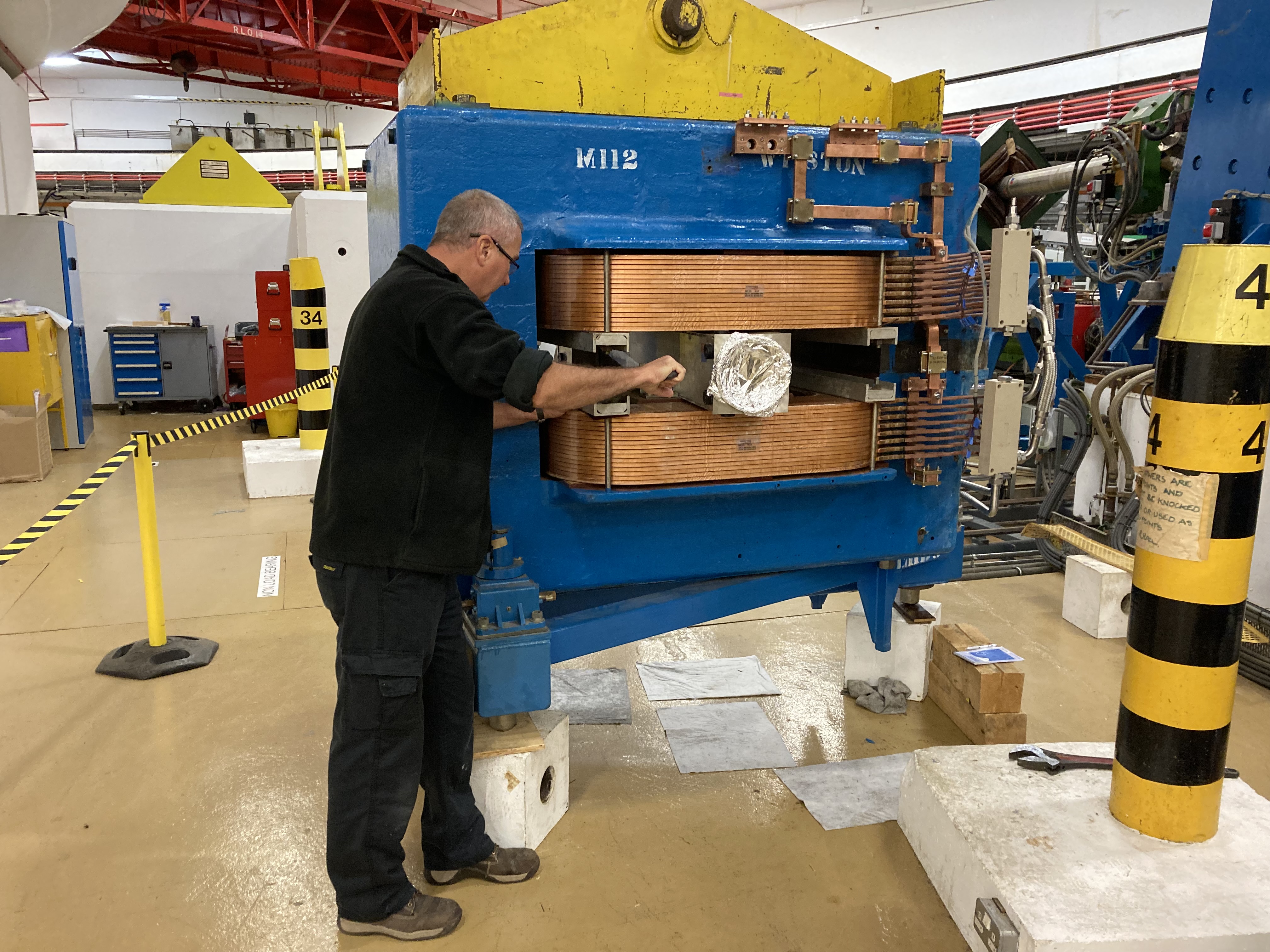 An engineer tightening bolts on a magnet in the accelerator hall