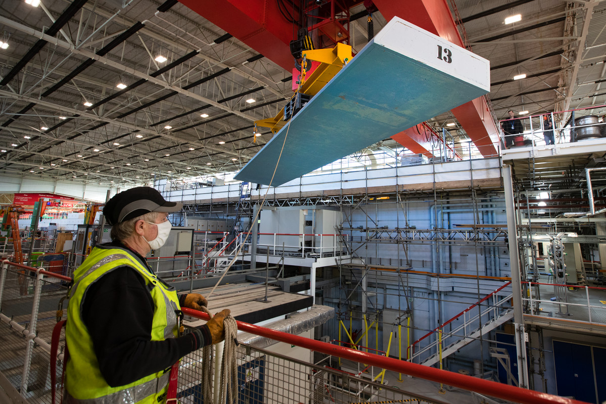 Roof lintel being craned off, with staff member directing